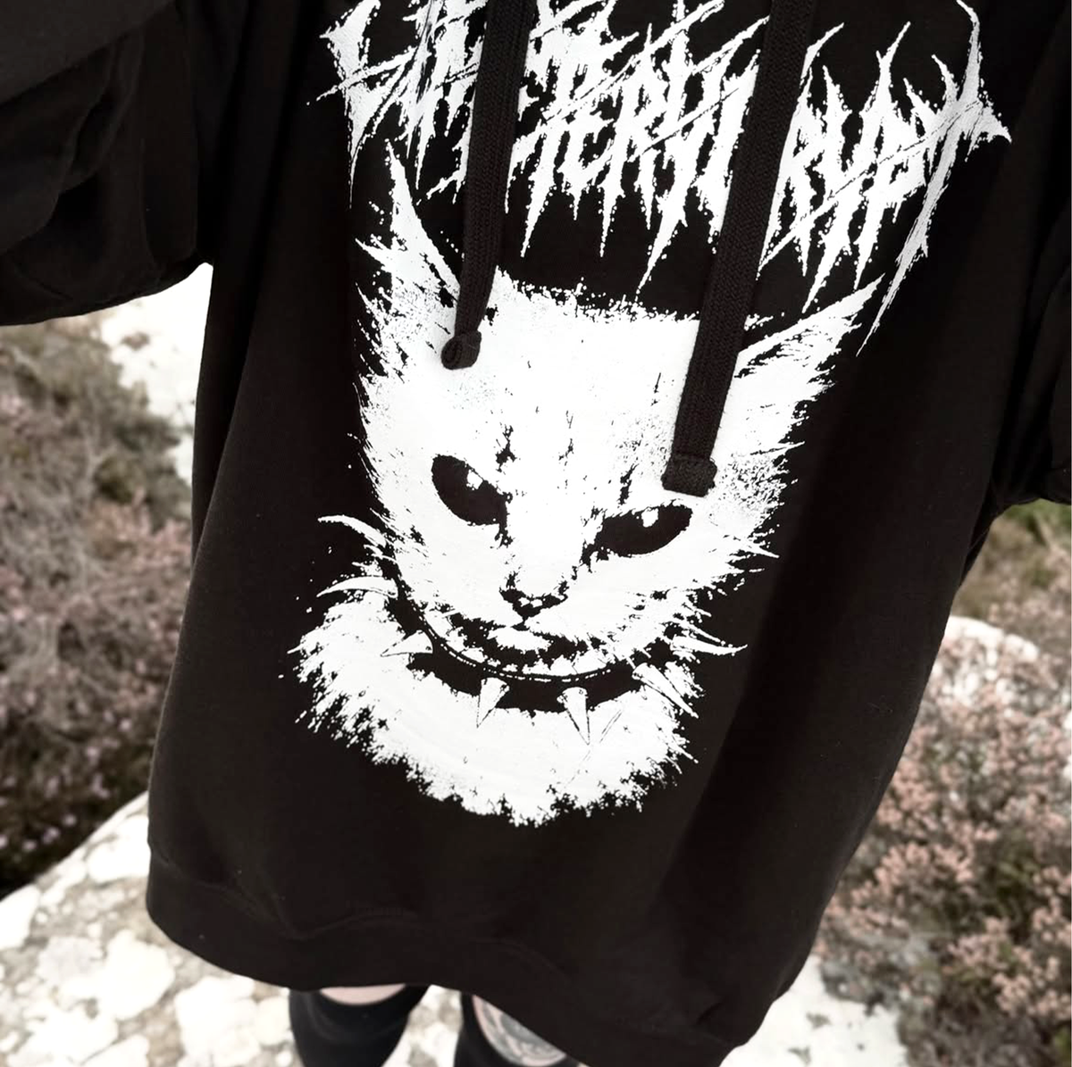 Close-up of the white cat print and gothic lettering on a black MEOW Hoodie
