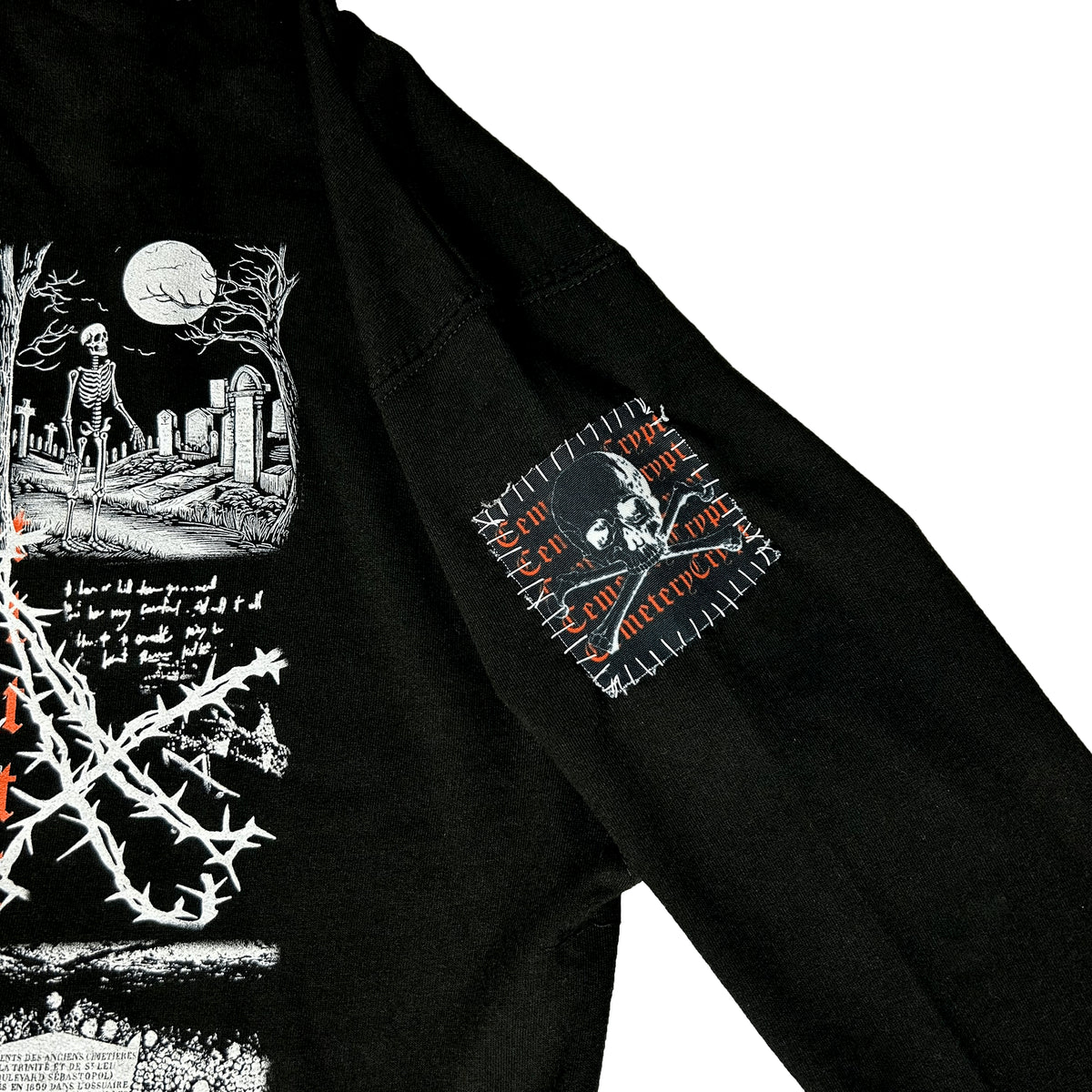 Close-up of the Catacombs Hoodie upper sleeve showing a small monochrome graphic with orange lettering