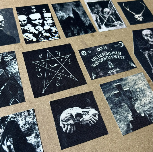 A selection of CemeteryCrypt black and white gothic canvas patches arranged on a brown background