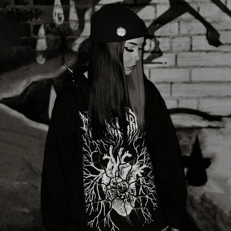 Model wearing the black Fractured Heart Hoodie with the white anatomical heart print visible