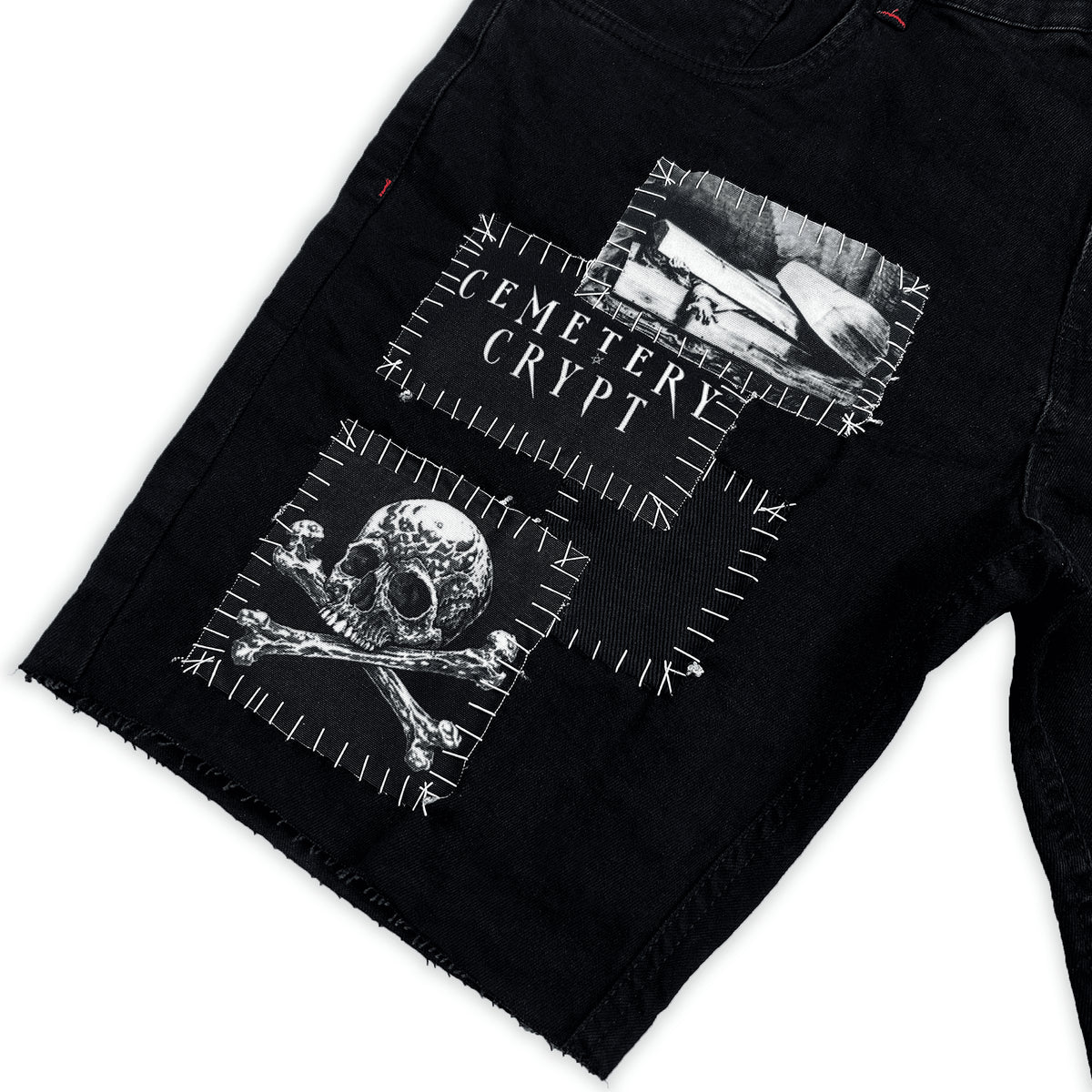 Close-up of the Cemetery Crypt lettering and skull-and-crossbones patches on the Rotten Denim Shorts