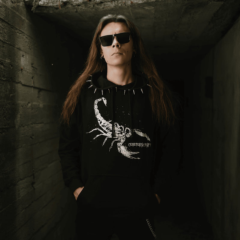 Model wearing sunglasses and the black Scorpion Hoodie, showing its large white scorpion print