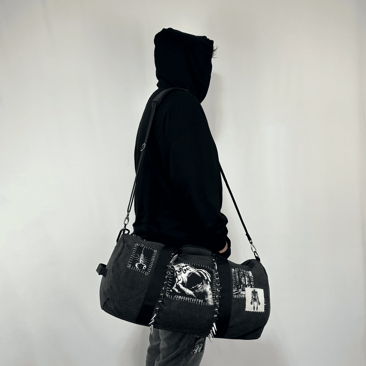 Side view of a model carrying the black Terror Barrel Bag from its shoulder strap