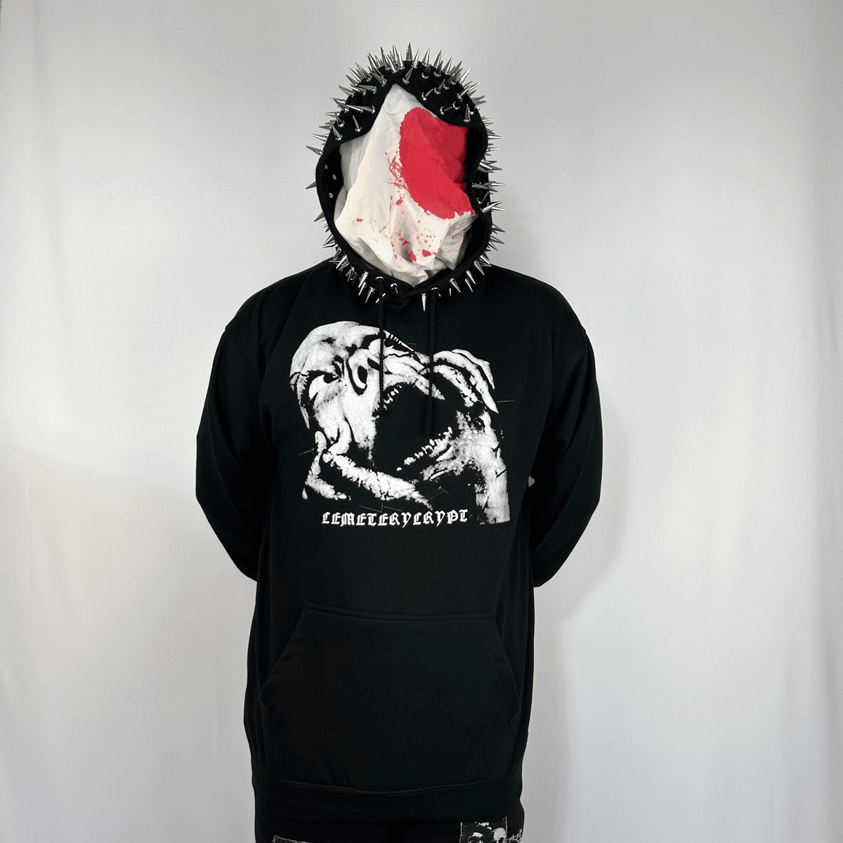 Front view of a masked model wearing the Terror Hoodie with the screaming face print and spiked hood visible